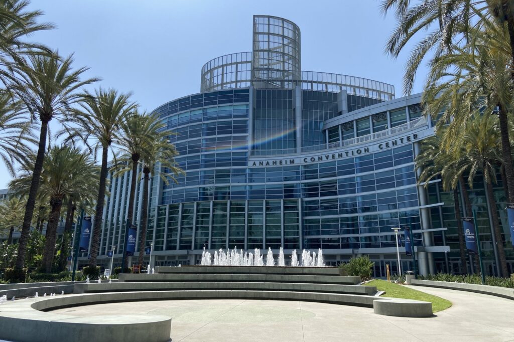 Glass entrance of the Anaheim Convention Center with palm trees and a fountain