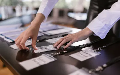 Hands laying out attendee name badges and lanyards on a table before an event