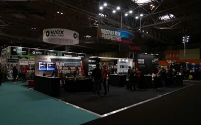 Lit trade show booths on a dark exhibit floor